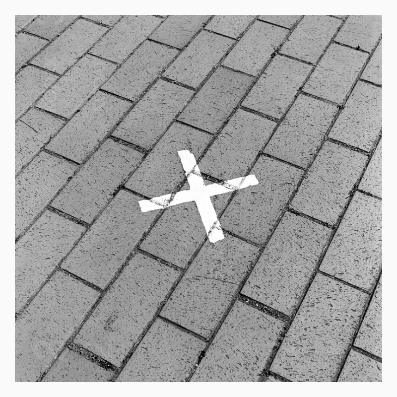 A photo of a white cross on the sidewalk made of bricks