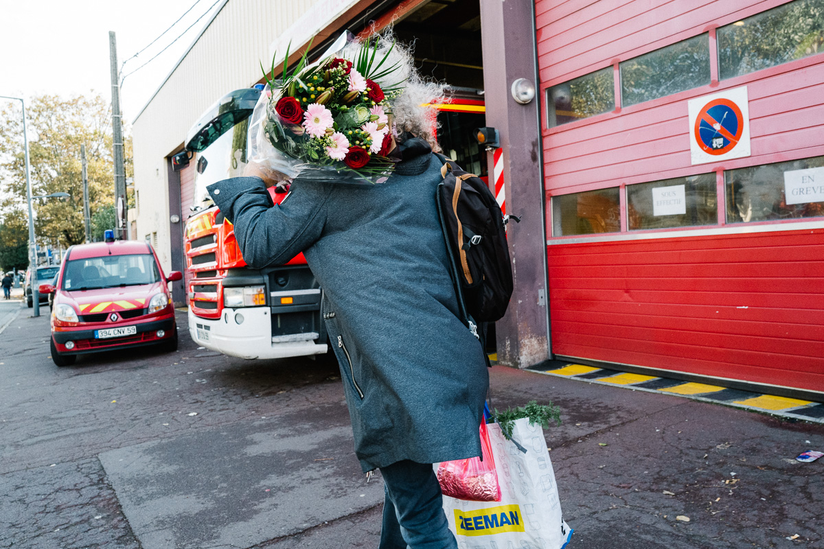Un homme passe devant la caserne de pompier du quartier de wazemmes à Lille en portant un bouquet de fleurs sur son épaule