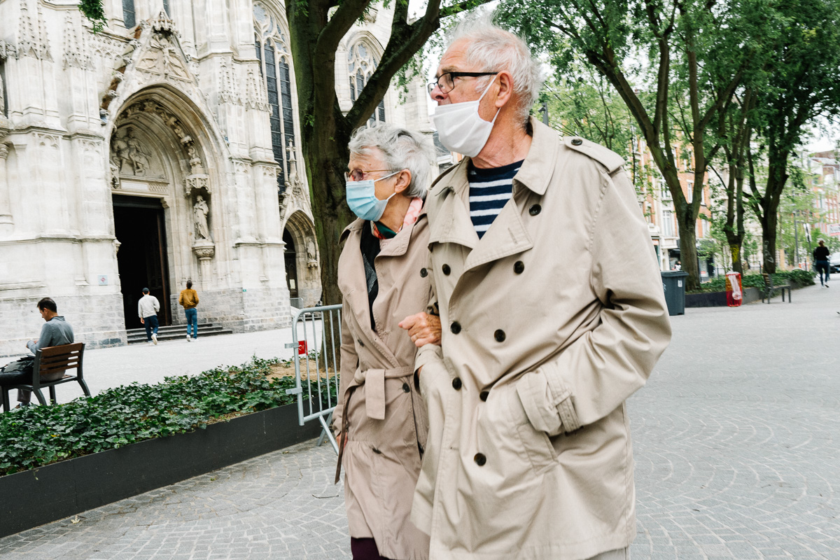 Un couple se promène à Lille en trenchcoat et en portant un masque sanitaire
