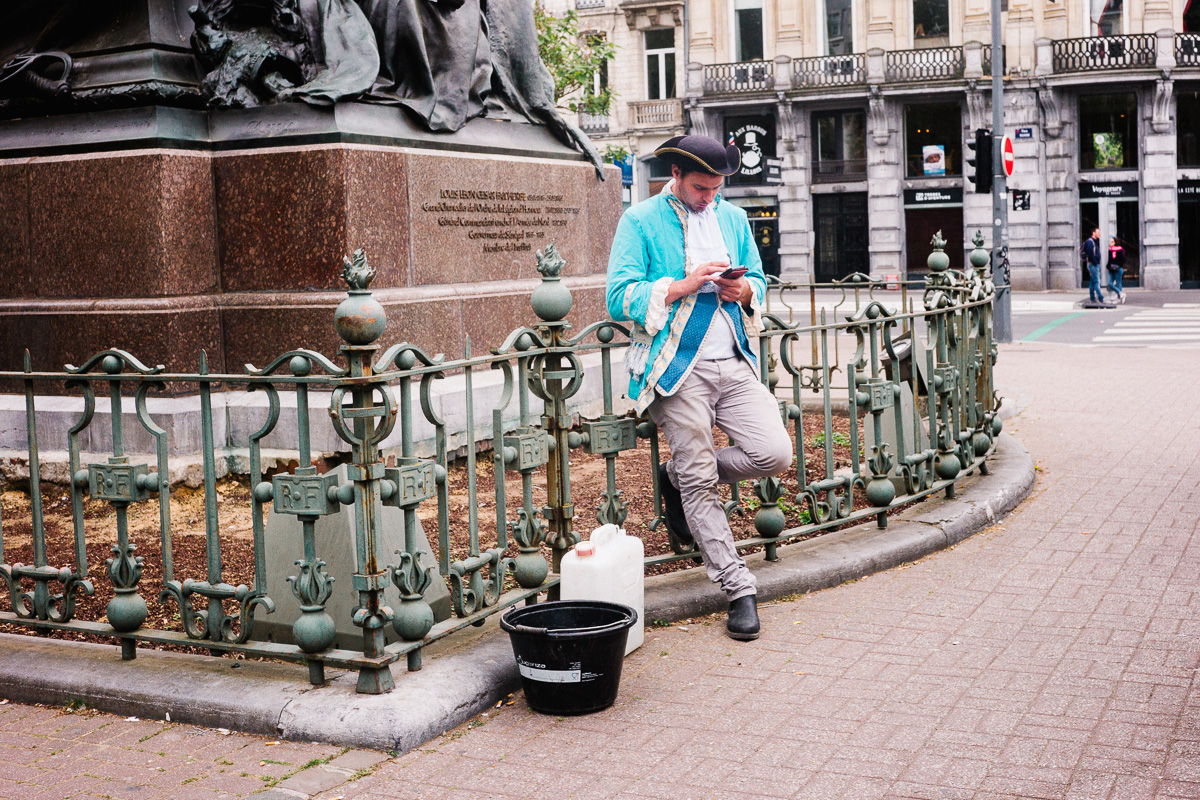 Un homme habillé en palefrenier consulte son smartphone place Richebé à Lille