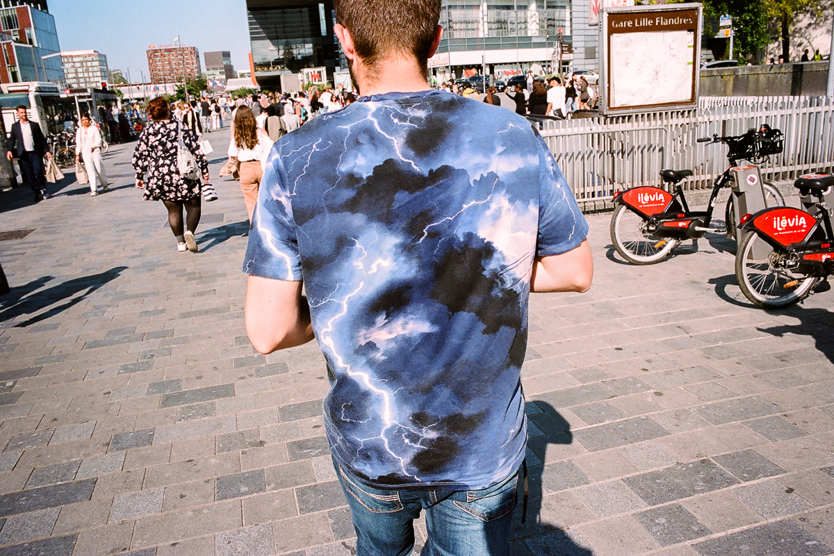 Un homme portant un teeshirt bleu avec des nuages et des éclairs se dirige vers Euralille
