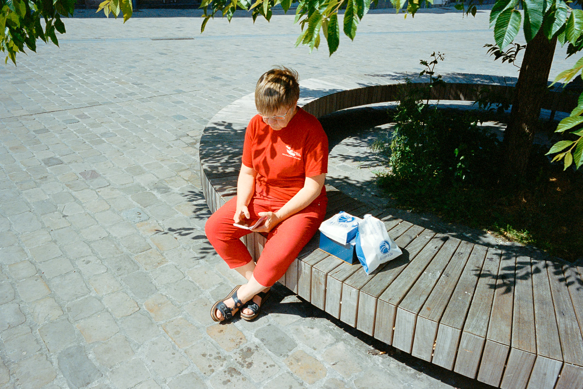 Une femme habillée en rouge consulte son smartphone assise sur un banc place Louise de Bettignies à Lille